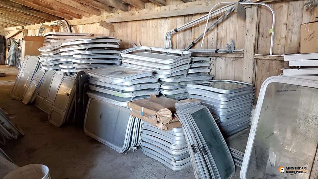 Airstream windows and parts stacked in barn